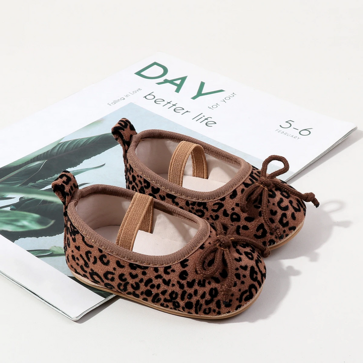 Pair of brown leopard-print baby shoes with brown elastic straps and toe bows