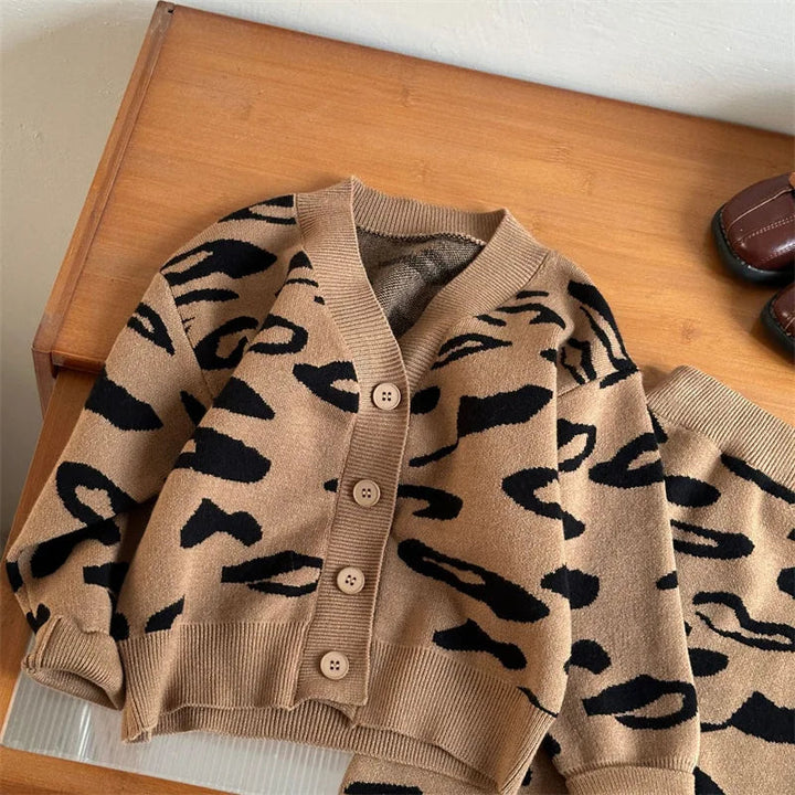 Brown button-front leopard-pattern cardigan and matching skirt on a wooden surface.
