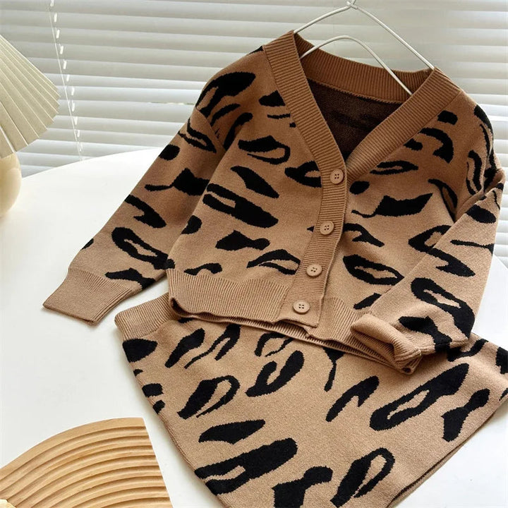 Brown leopard-pattern knit cardigan hanging above a matching skirt.