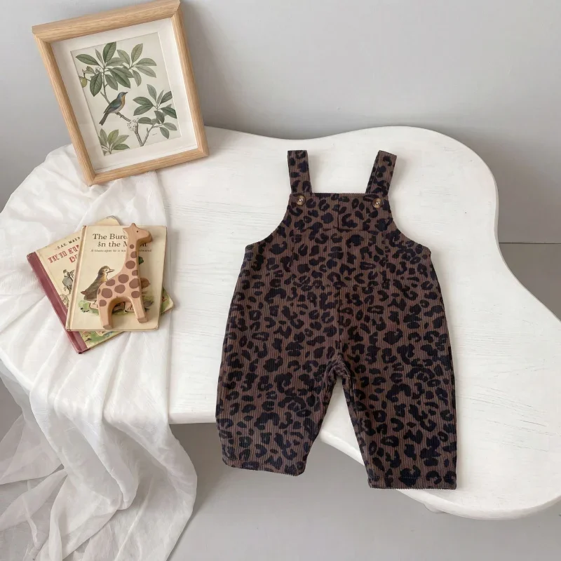 Brown leopard print overalls laid out on a curved white chair beside books