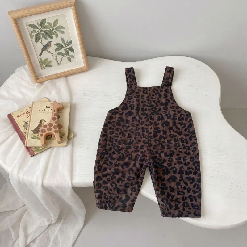 Full-length brown leopard print overalls displayed on a white chair