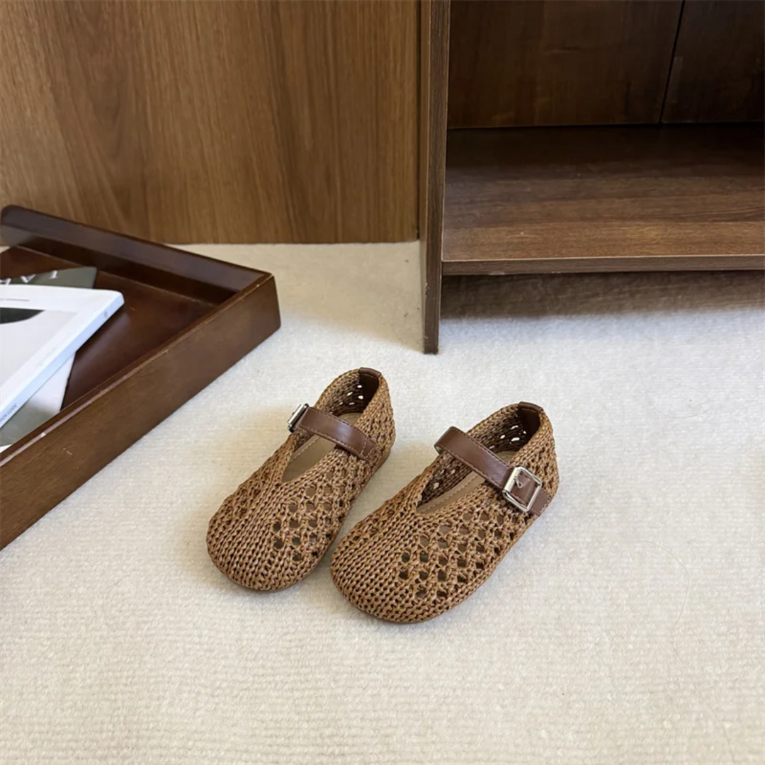 Pair of brown openwork Mary Jane flats beside an open wooden cabinet