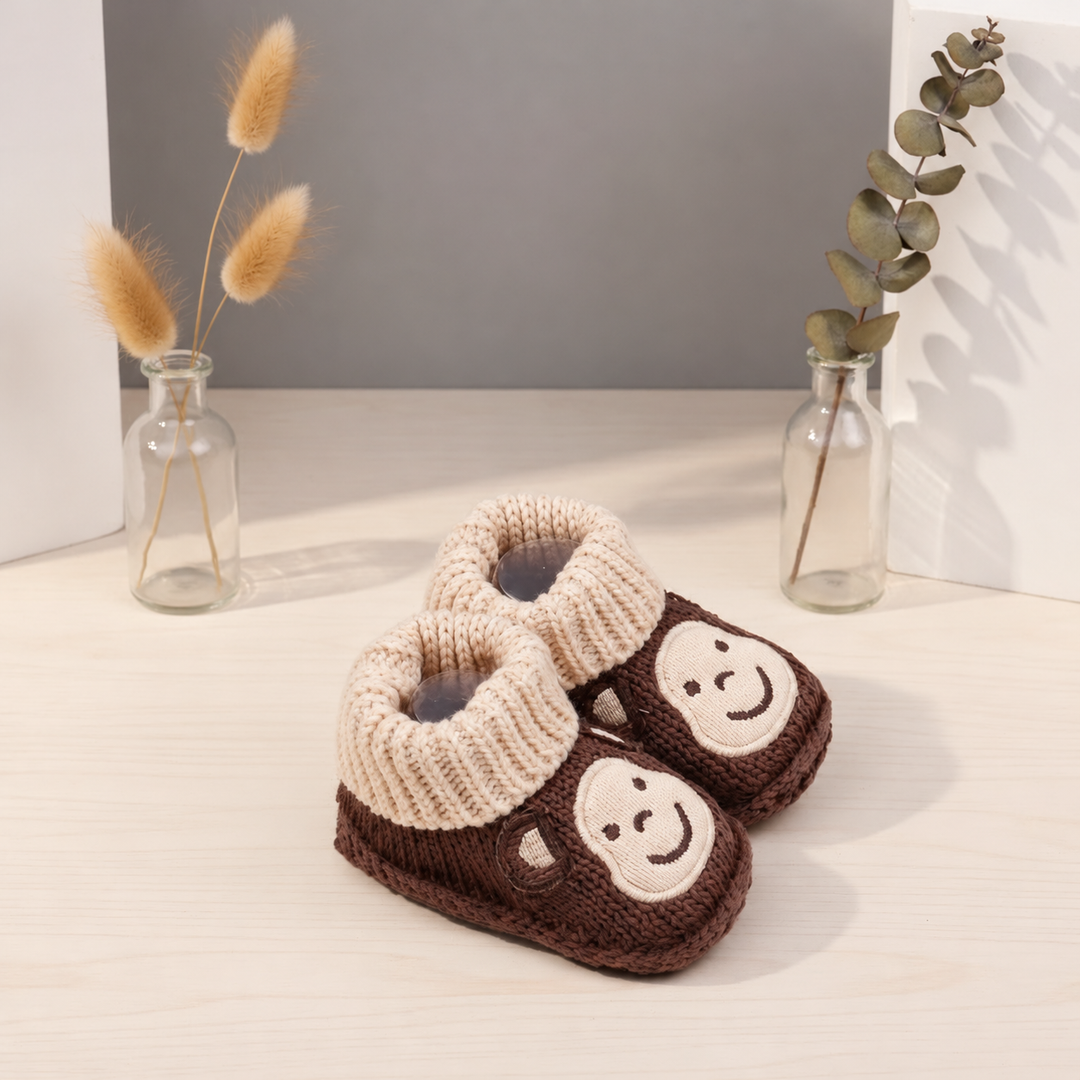 Brown monkey knitted booties with beige cuffs, shown at an angle