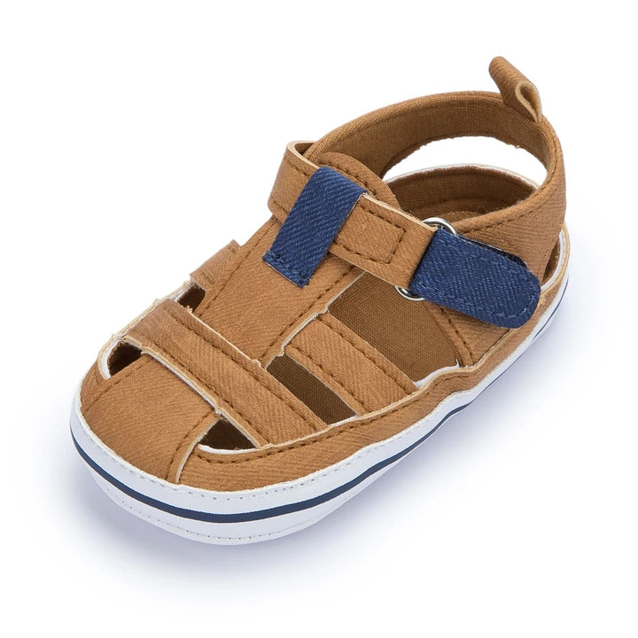 Brown baby sandal with navy strap accents and a white sole