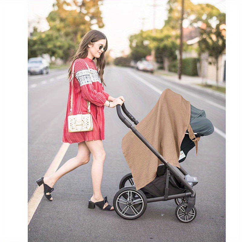 Brown nursing scarf draped over the canopy of a stroller outdoors