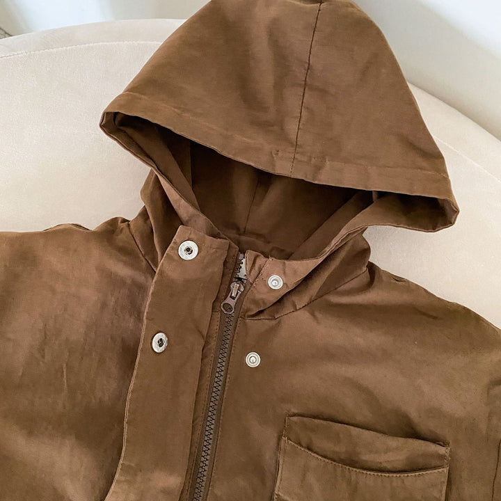 Brown parka close-up showing the hood, zipper, snap fasteners, and chest pocket