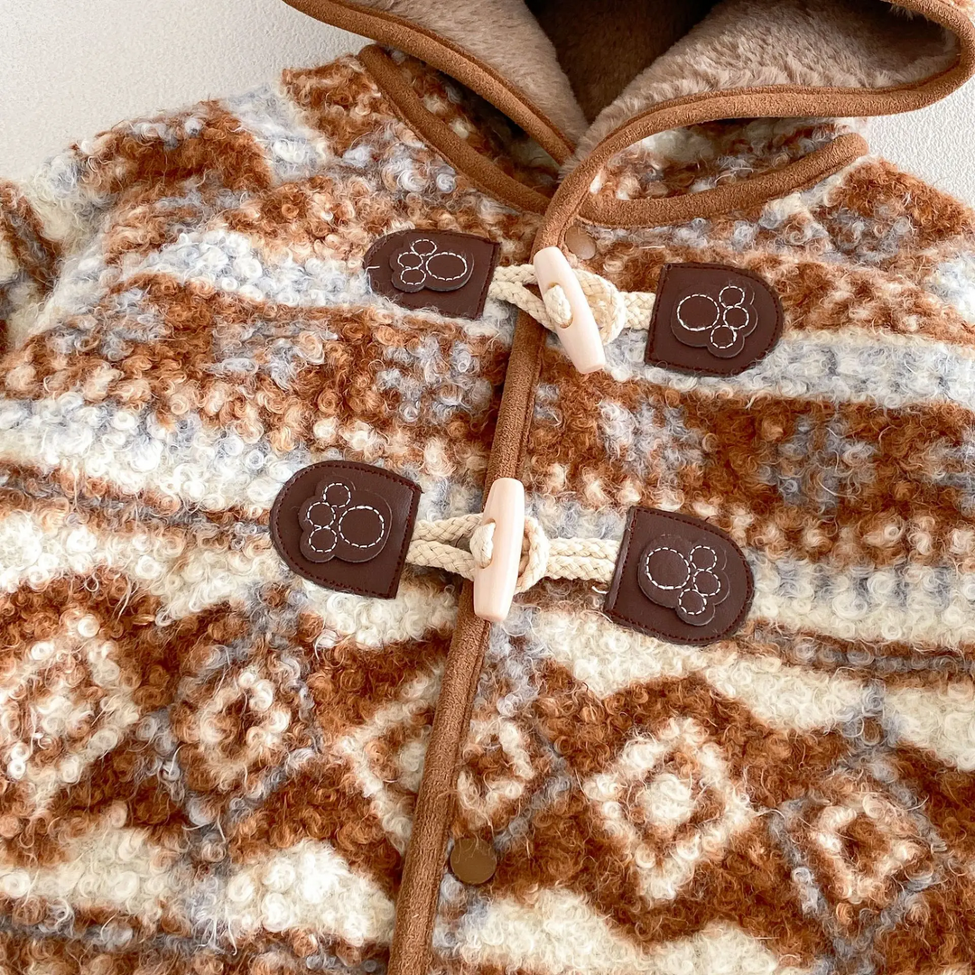 Close-up of two toggle closures and contrasting piping on the brown patterned jacket