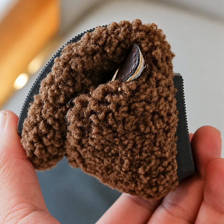 Brown plush shoe bent by hand to show its flexible sole