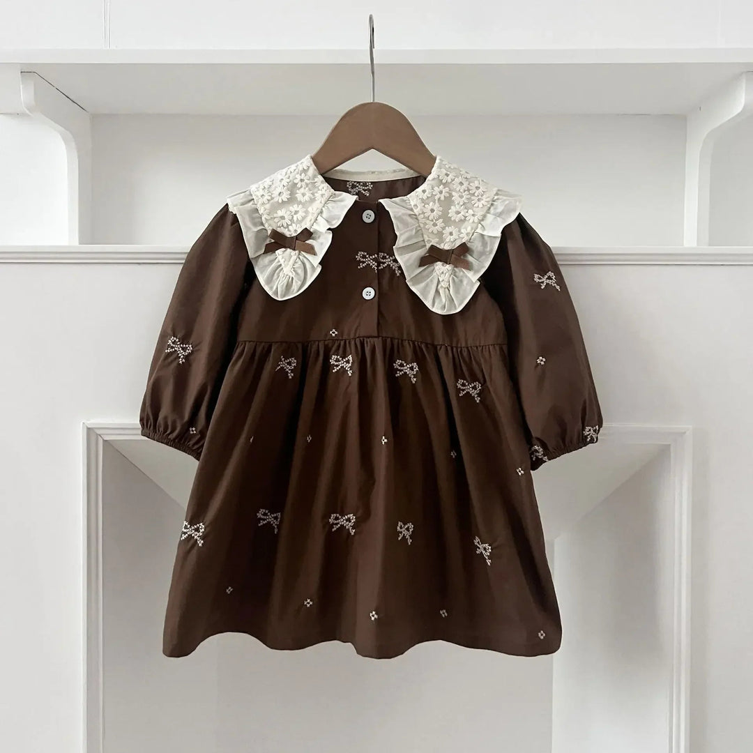 Brown A-line dress with a cream lace collar, matching bows, and gathered sleeves