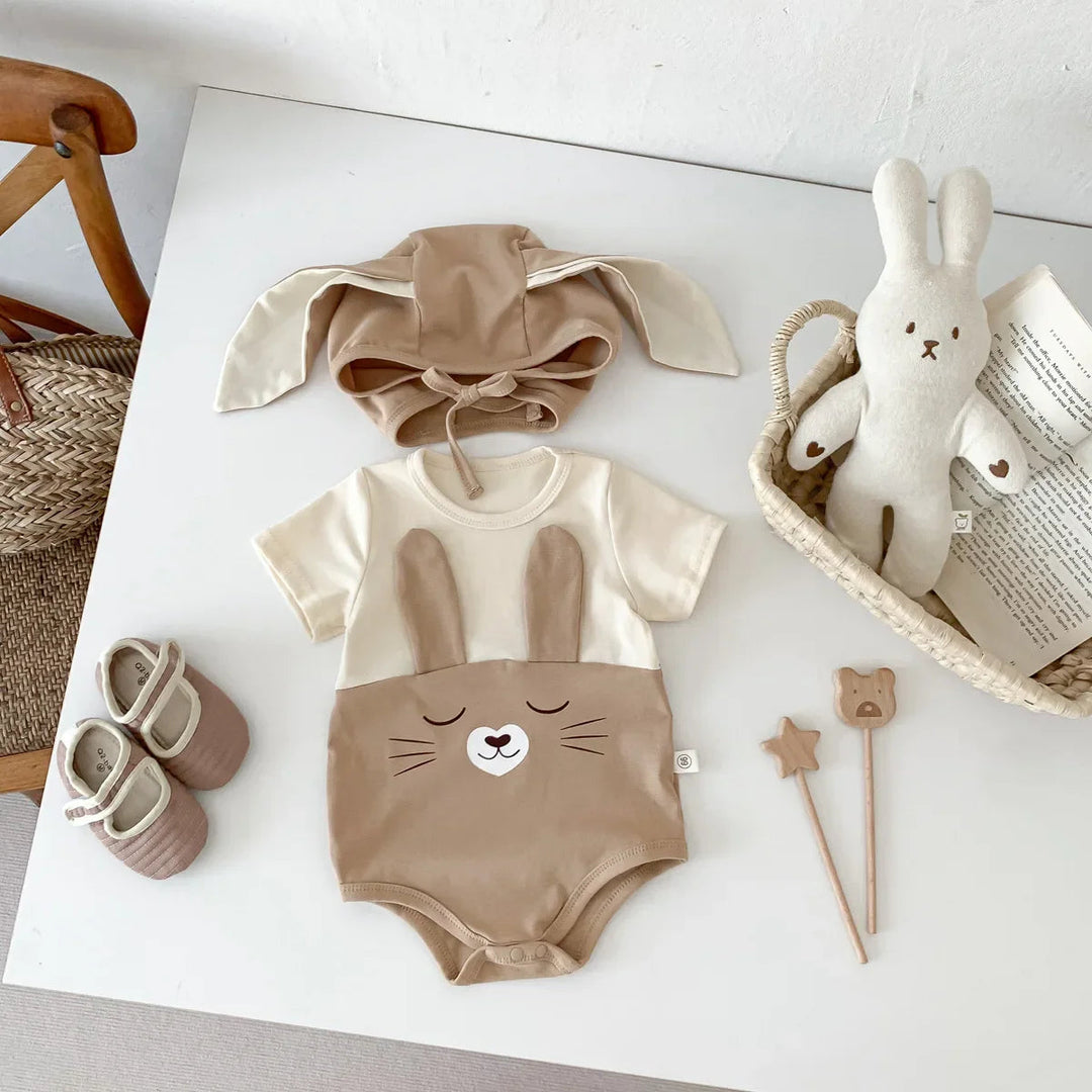 Brown short-sleeve bunny bodysuit and matching floppy-ear cap arranged on a white surface
