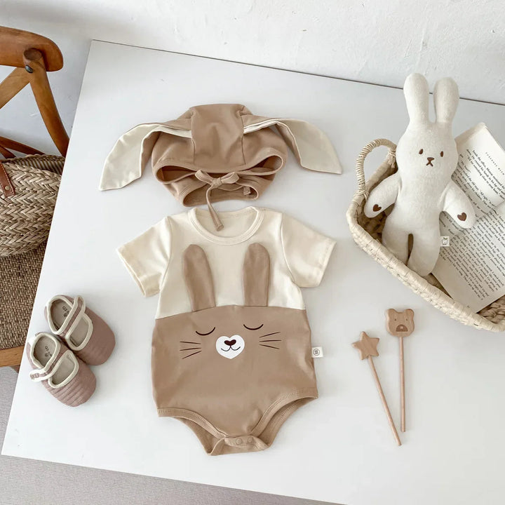 Brown short-sleeve bunny bodysuit and matching floppy-ear cap arranged on a white surface
