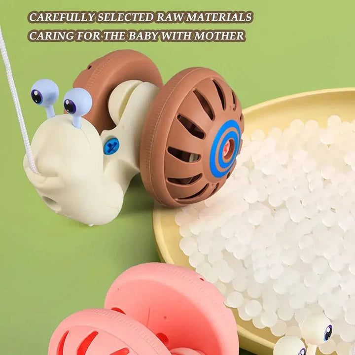 Brown and cream snail pull toy beside pale plastic pellets