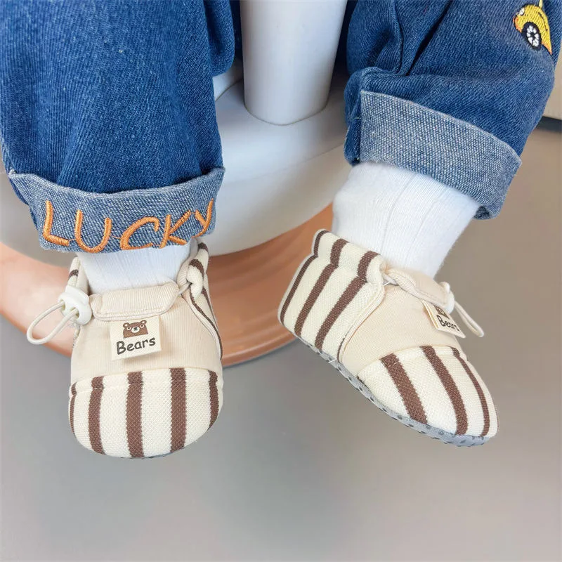 Brown striped baby shoes worn with white socks and cuffed jeans