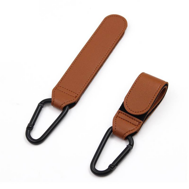 Two brown stroller hooks lying flat, with one strap extended and one folded