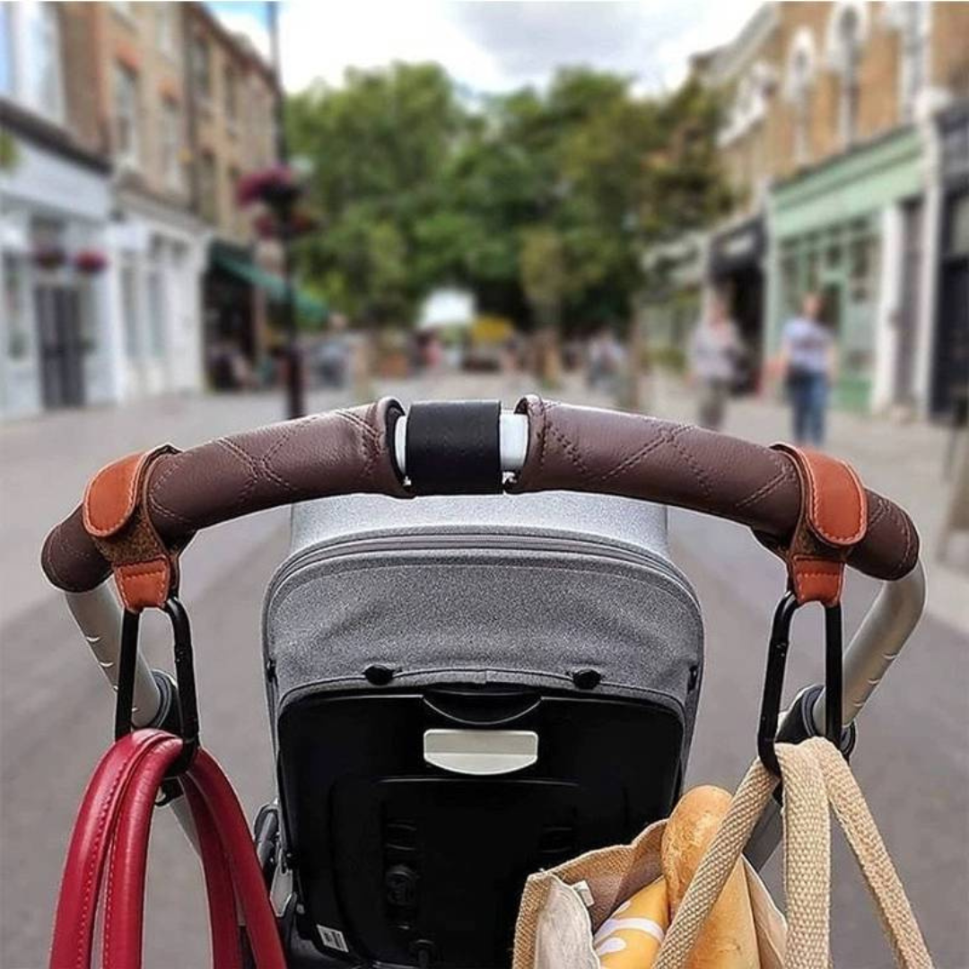 Brown stroller hooks holding two bags on a stroller handlebar during a walk