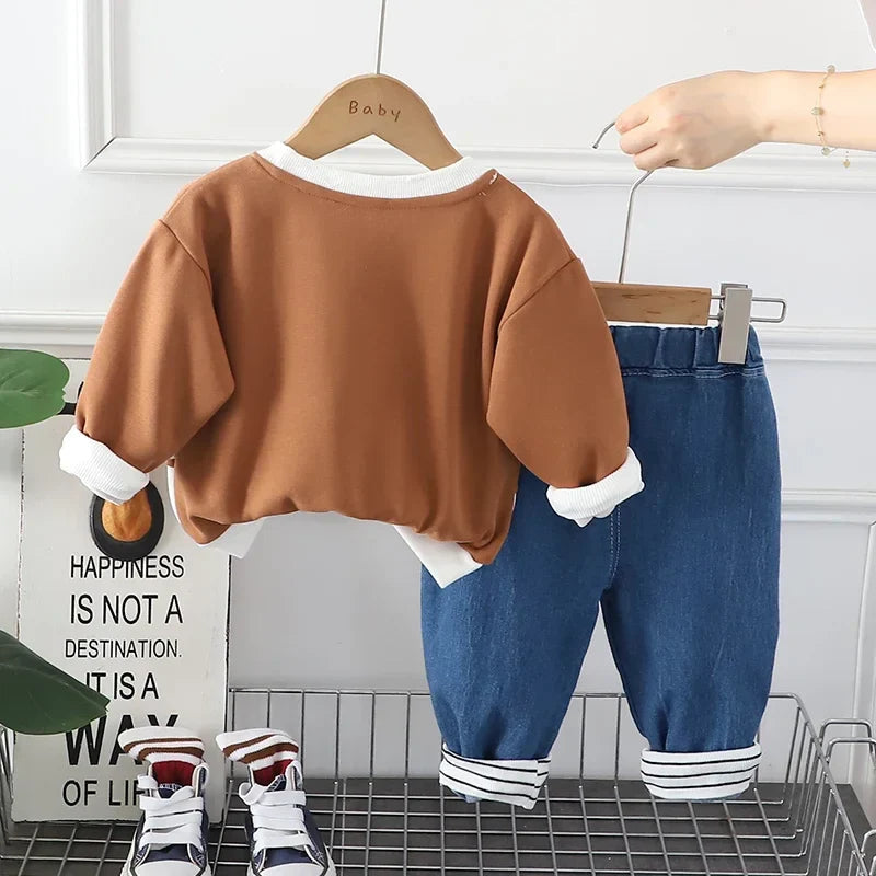 Back view of the brown sweatshirt and blue pants with striped ankle cuffs