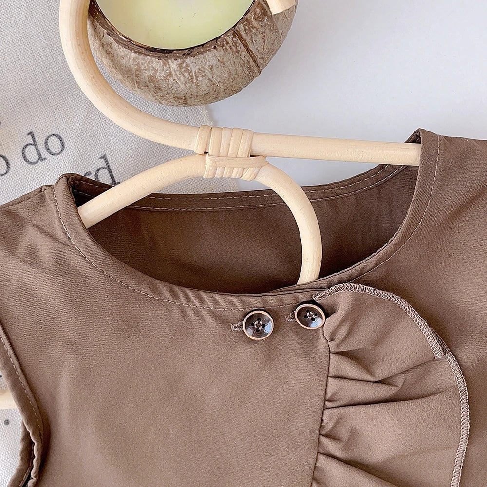 Close-up of two button accents and the curved ruffle at the brown top&
