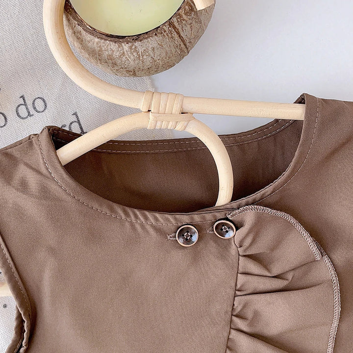 Close-up of two button accents and the curved ruffle at the brown top&
