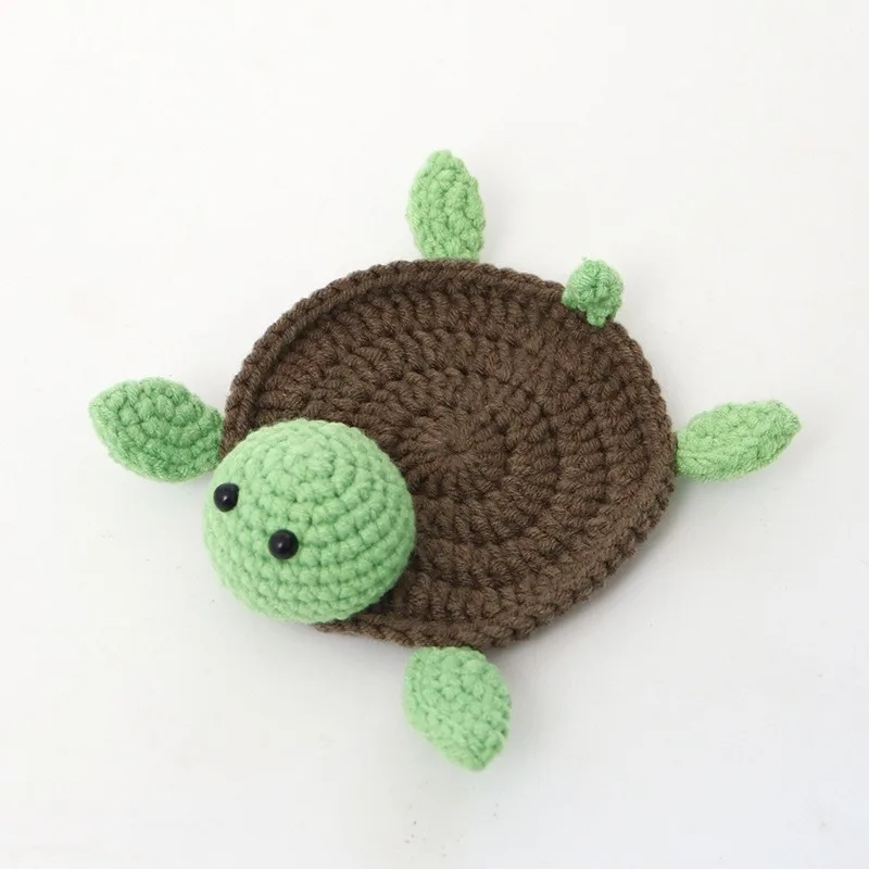 Brown tortoise coaster with a round crocheted shell and light green head and feet