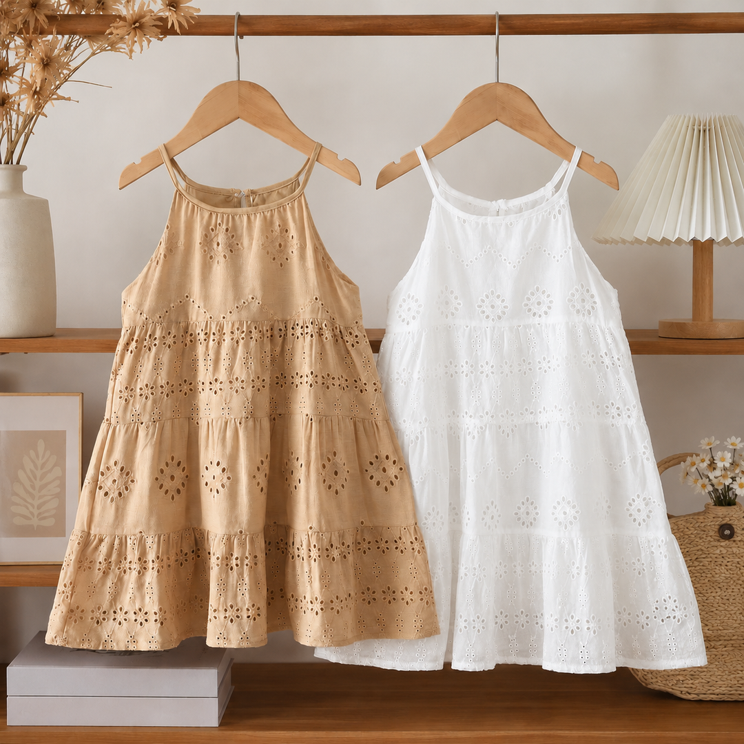 Brown and white tiered eyelet dresses hanging side by side on wooden hangers