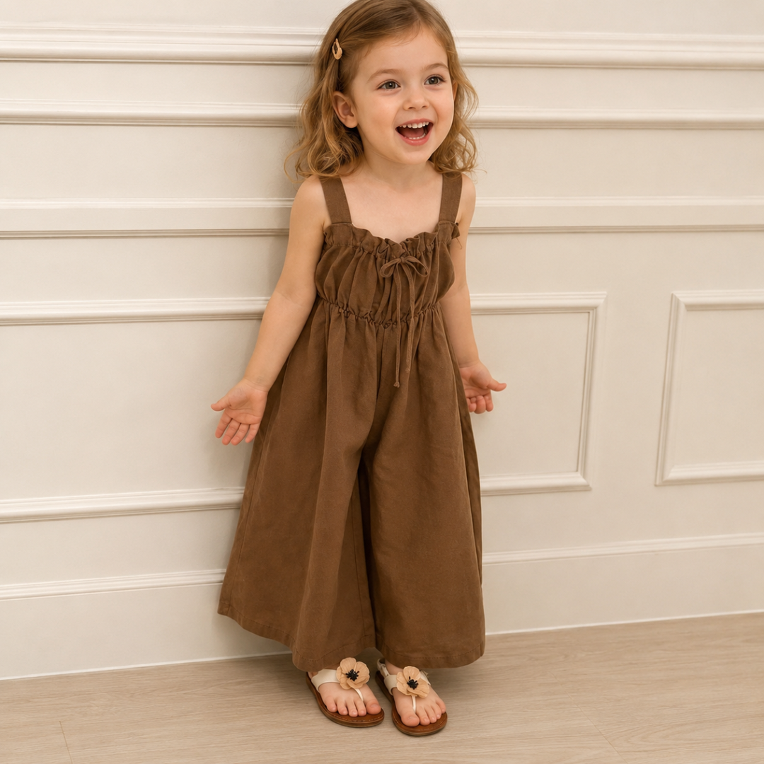 Child wearing the brown wide-leg jumpsuit with a gathered neckline and front bow