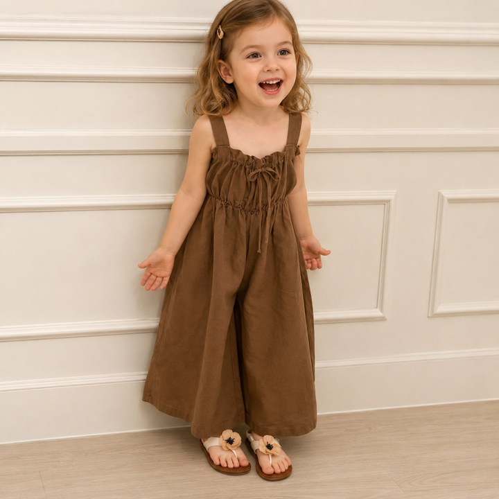 Child wearing the brown wide-leg jumpsuit with a gathered neckline and front bow