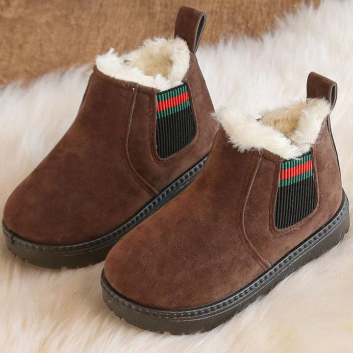 Brown plush-lined winter boots with black rubber soles displayed together on a white rug.