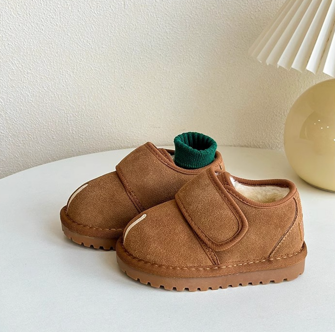 Brown winter shoes on a white tabletop, with a green sock tucked into the rear shoe.
