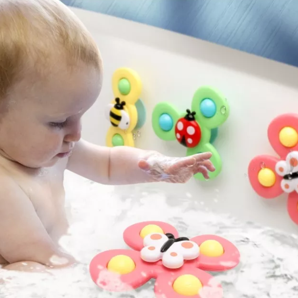 Child playing in a bathtub with colorful bug-themed spinners on the tub wall and in the water