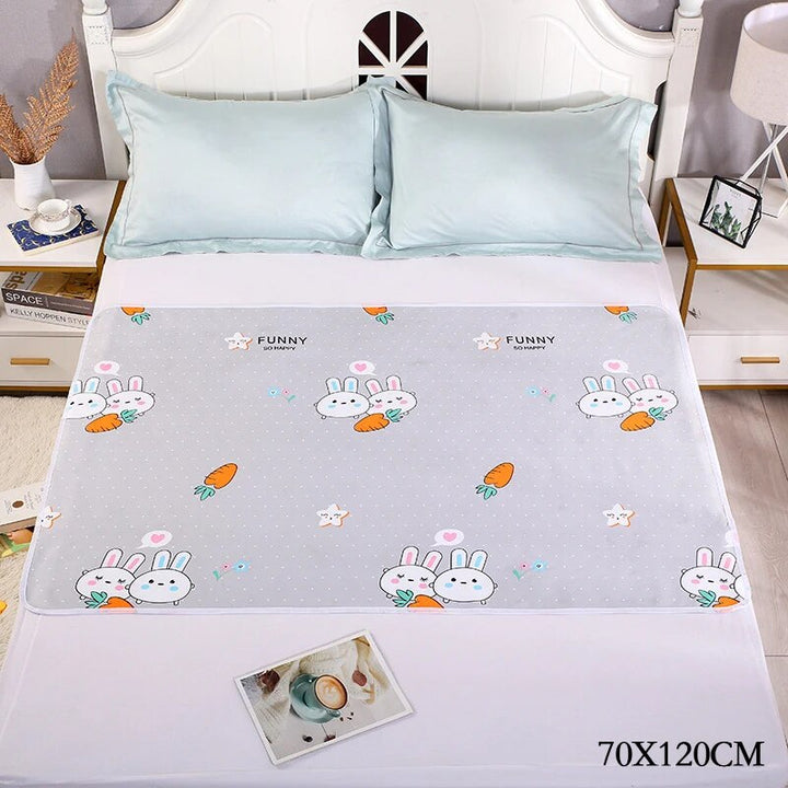 Gray bunny-and-carrot changing mat spread flat on a bed, labeled 70 x 120 cm.