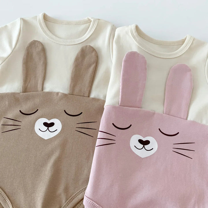 Close-up of bunny faces and fabric ears on brown and pink baby bodysuits