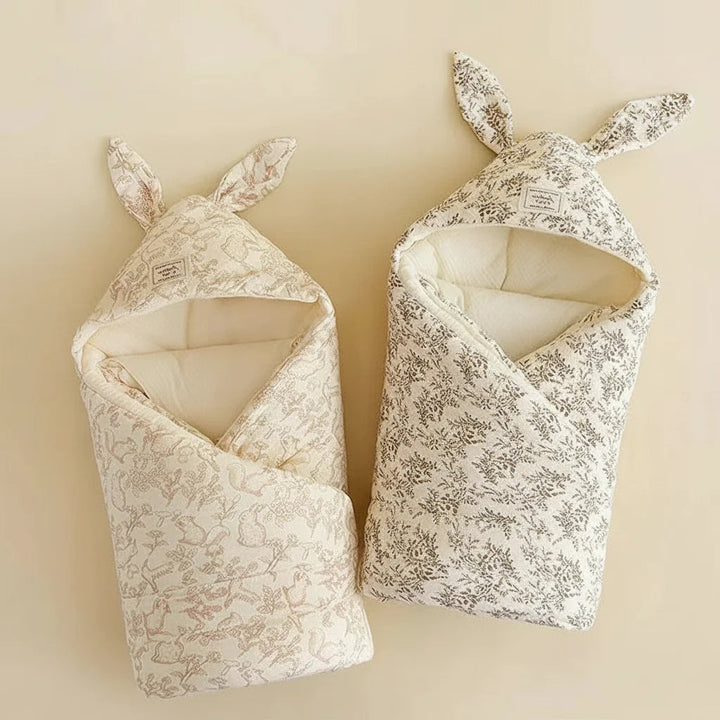 Bunny and botanical print swaddle blankets with folded fronts and bunny-ear hoods