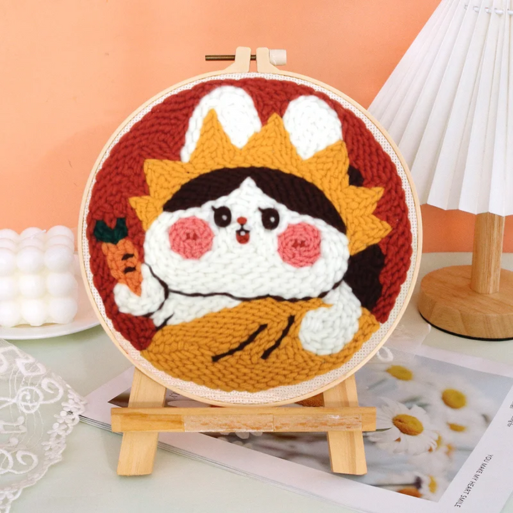 Bunny punch needle design with white ears, rosy cheeks, and a carrot against a red background