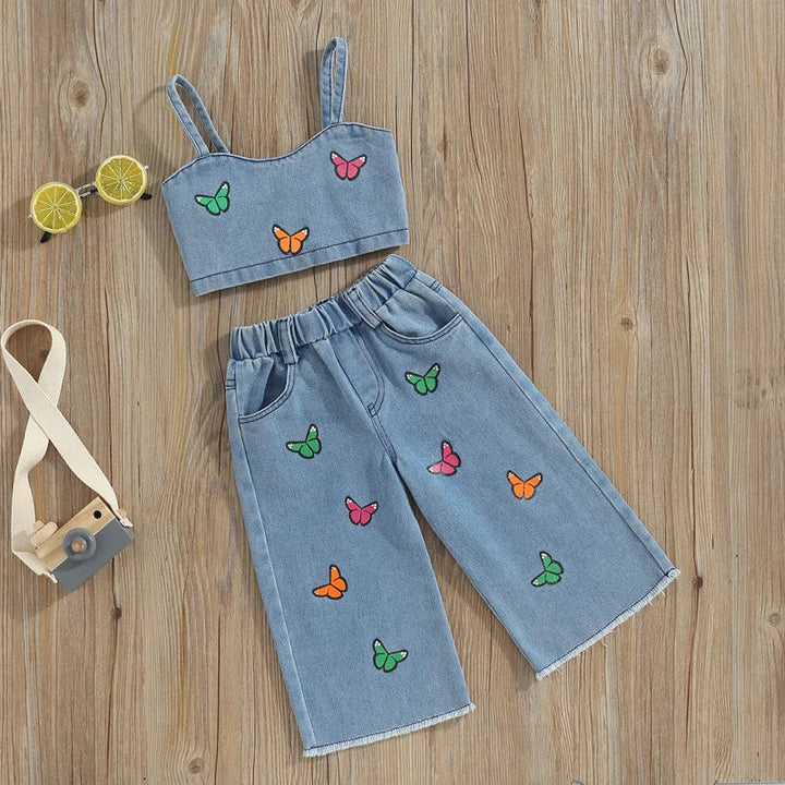 Front view of the butterfly denim top and matching pants arranged on a wood surface