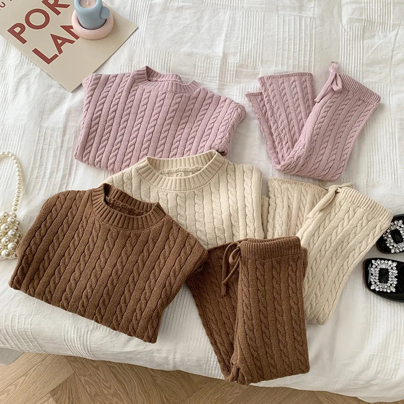 Cable-knit sweater and pants sets in pink, beige, and brown, arranged together