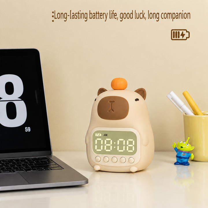 Rechargeable capybara alarm clock on a white desk beside a laptop.