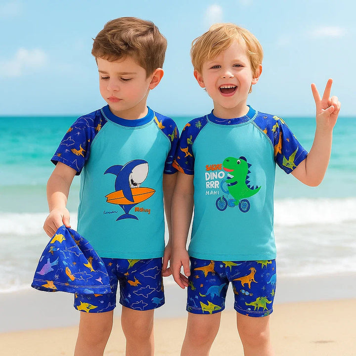 Two children wearing blue shark and cycling dinosaur swim sets on a beach