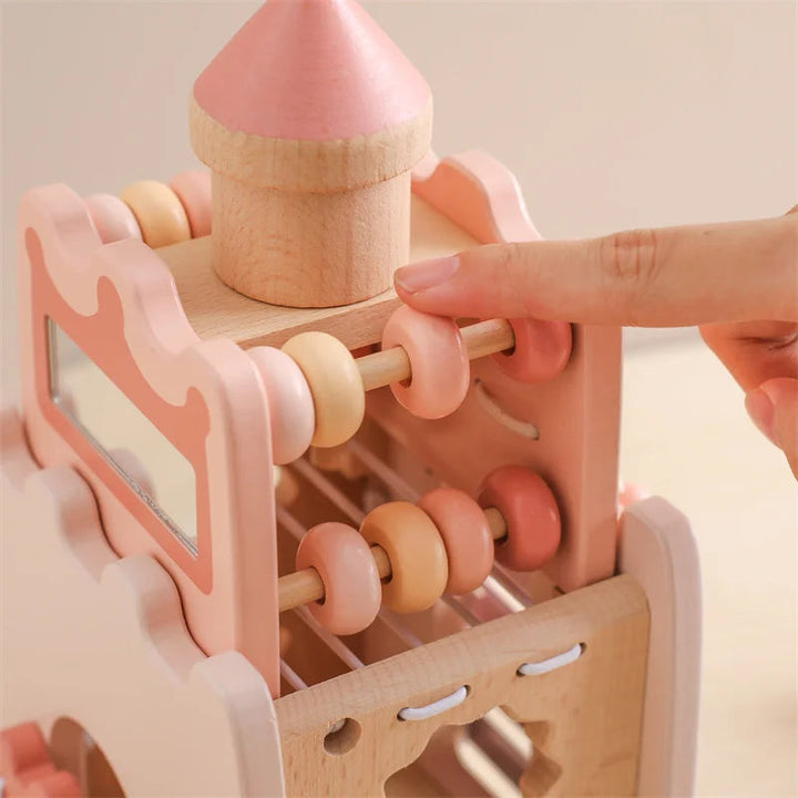 Finger moving pink and natural wood beads along a rod on the music tower