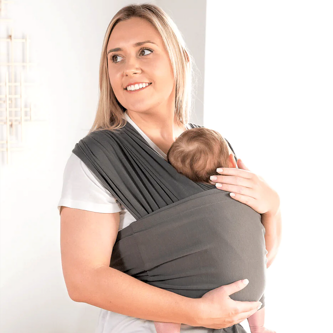 Parent cradling a baby against the chest in a charcoal gray wrap-style carrier