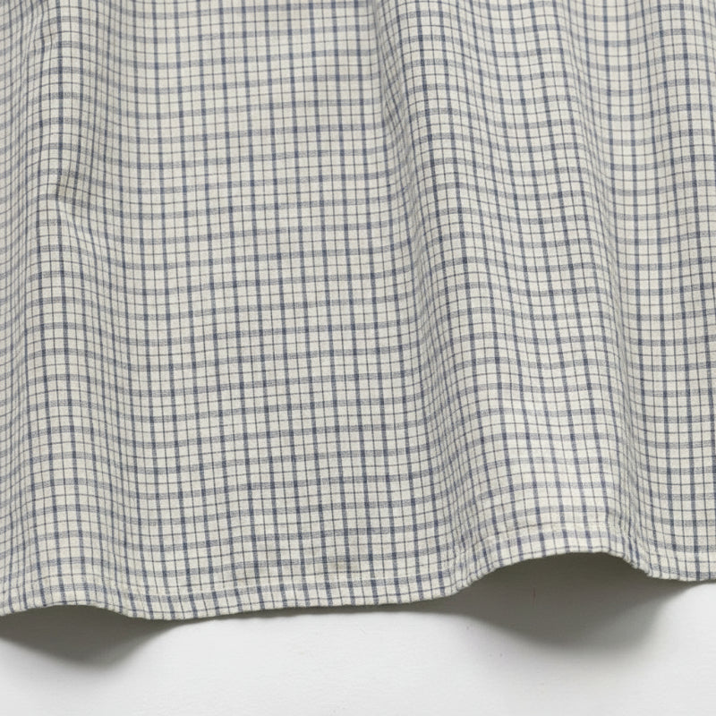 Close-up of the fine check pattern and stitched hem of the cotton dress