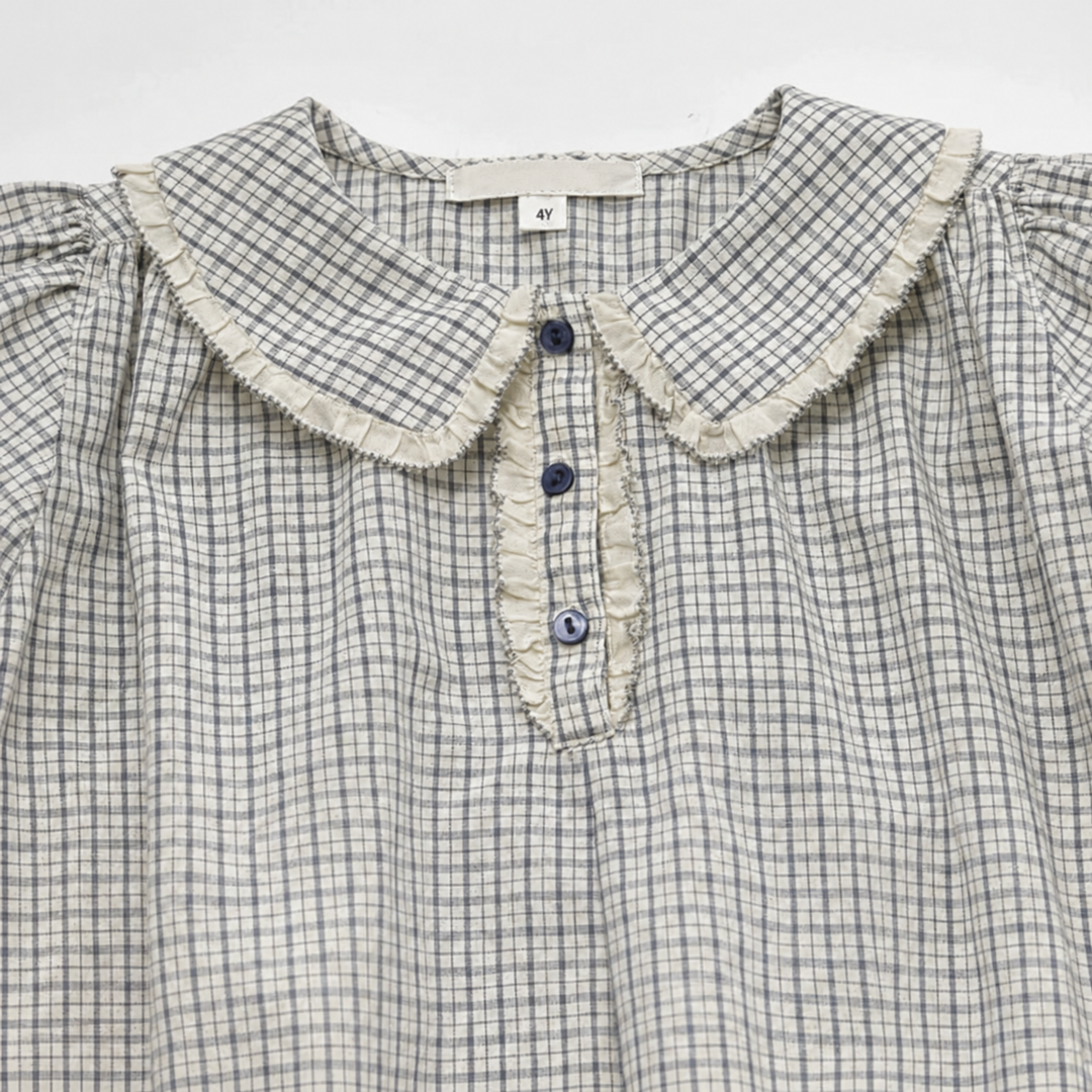 Close-up of the check dress collar with white ruffle trim and a three-button front