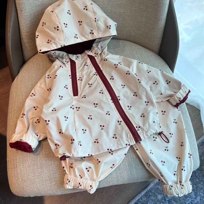Cherry-print jacket and matching pants with elastic ankle cuffs arranged on an armchair.