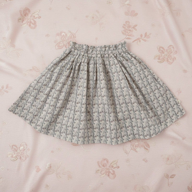 Printed skirt with a gathered elastic waistband laid on pink floral fabric