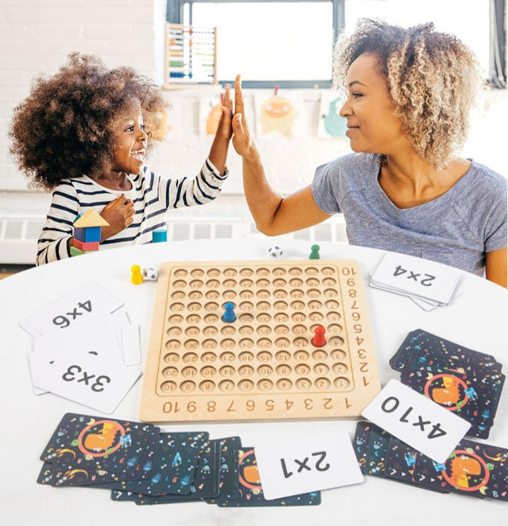 Child and adult high-fiving over a wooden multiplication board and math cards
