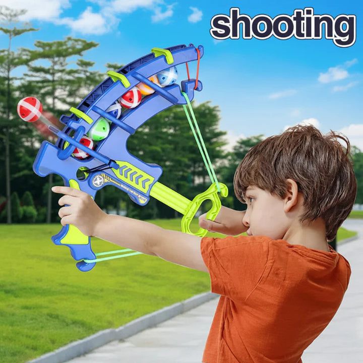 Child aiming a blue sticky ball launcher outdoors