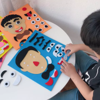 Child arranging removable eyes and mouth pieces on a blue felt face board