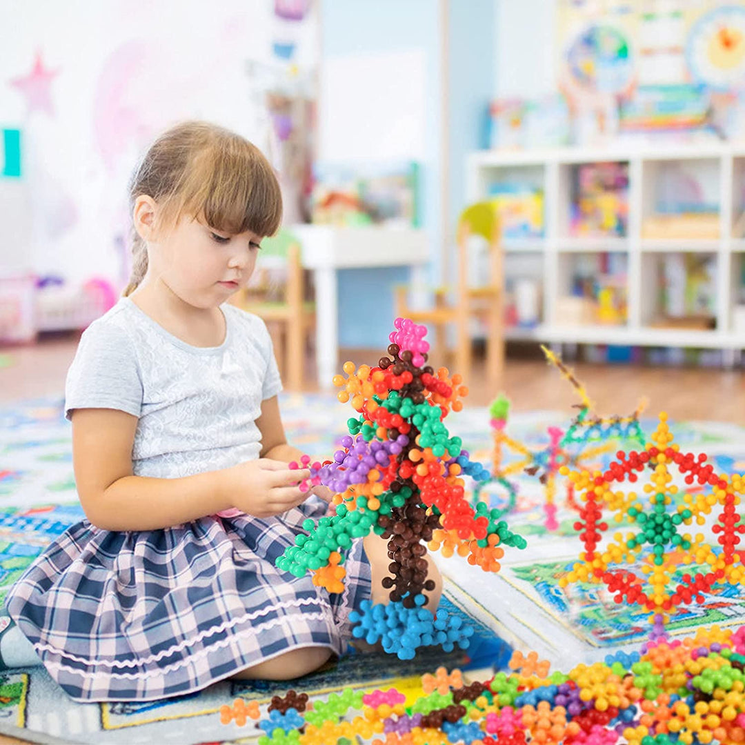 Child assembling colorful snowflake blocks with finished models nearby