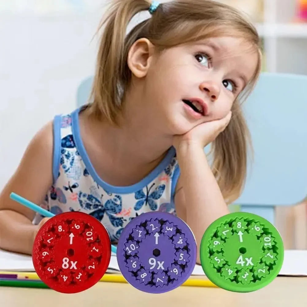 Child at a desk with three colorful multiplication spinners.