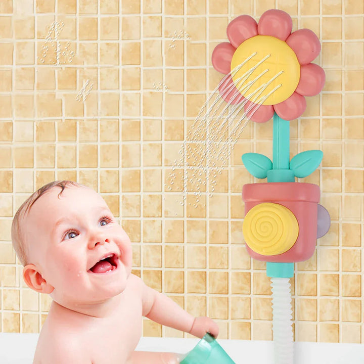 Child in a bathtub beside a red flower bath sprayer spraying water