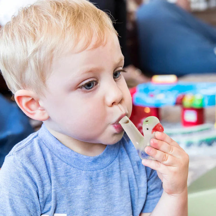 A child blowing a hand-painted ceramic bird whistle